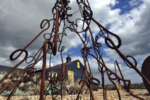 Picture by Roger Bamber: 1 September 2007 : Prospect Cottage, the former home of the late artist and film director Derek Jarman at Dungeness,on Romnet Marsh, Kent. The house and its dry shingle garden is photographed through one of his many sculptures made from iron and driftwood., Copyright: Topfoto !ACHTUNG AUFNAHMEDATUM GESCHÄTZT! UnitedArchives1388186