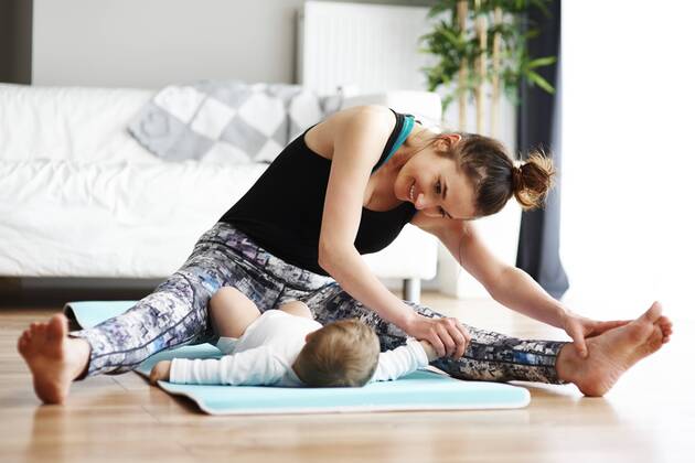 Mother with baby exercising on yoga mat at home model released Symbolfoto property released  ABIF00335