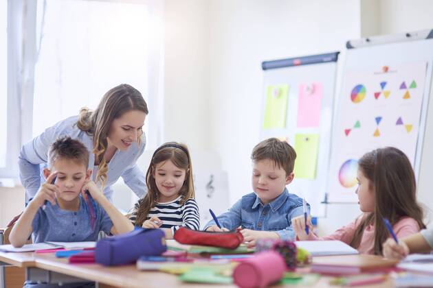 IMAGO Creative: Gesellschaft, Schule, Schulanfang Smiling teacher helping pupils with their tasks in class model released Symbolfoto property released  ABIF00378