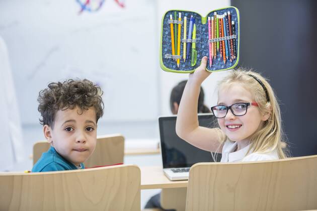 Portrait of schoolboy and schoolgirl with laptop and pencil case in class model released Symbolfoto property released  WESTF24227