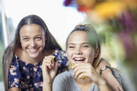 Happy teenage girl watching friend applying mascara model released Symbolfoto property released  ZEF15650