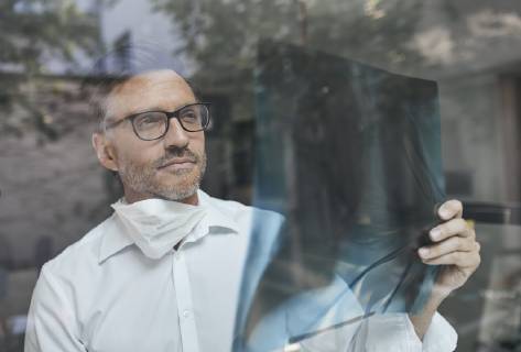 Portrait of radiologist behind windowpane looking at x-ray image model released Symbolfoto  PNEF00820