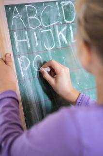Back view of girl writing alphabet on chalkboard model released Symbolfoto  JFEF00897