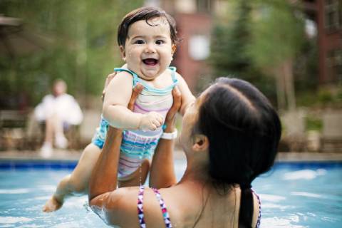 A Japanese American mother swims and holds her 10 month old baby girl in a swimming pool., Breckenridge Colorado USA model released Symbolfoto Copyright: StevexGlass GLST002715