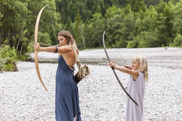 Mother and daughter aiming with bow and arrow in the nature model released Symbolfoto  TCF05787