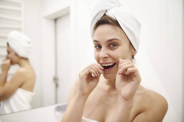 Portrait of young woman using dental floss in bathroom model released Symbolfoto property released ABIF00989