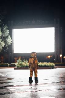 Spaceman on a square at night attracted by shining projection screen model released Symbolfoto  VPIF00754