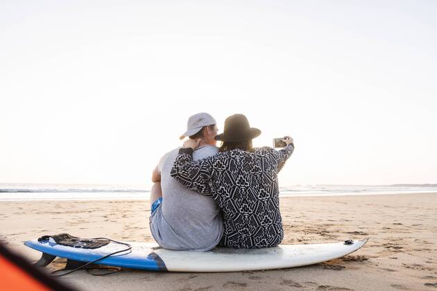 IMAGO Creative: Ende des Sommers Couple camping on the beach, taking smartphone selfies model released Symbolfoto  UUF15155