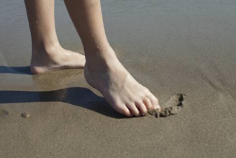 Child drawing in wet sand with foot, cropped  Copyright: AntoinexArraou B58940216