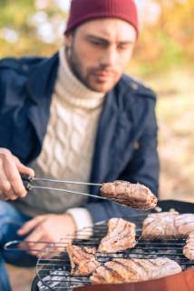  Man cooking meat on charcoal grill model released Symbolfoto  Copyright: xLightFieldStudiosx Panthermedia20174851
