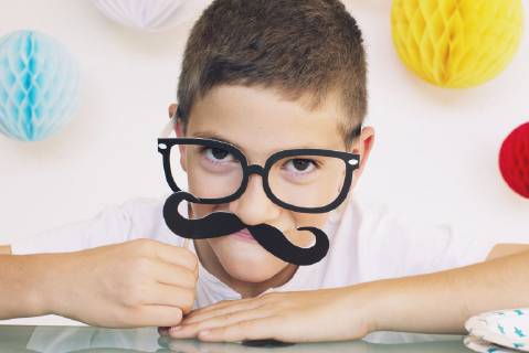 Boy wearing fake mustache and glasses at a birthday party  Copyright: Anne-SophiexBost B21789623