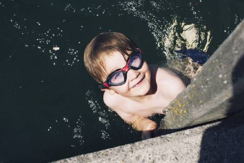 Boy with goggles swimming in water  Copyright: Anne-SophiexBost B53815531