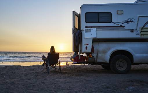 Chile, Arica, woman sitting next to camper on the beach at sunset model released Symbolfoto property released SSCF00079