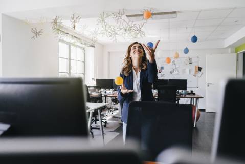 Happy businesswoman juggling balls in office model released Symbolfoto property released  KNSF02841