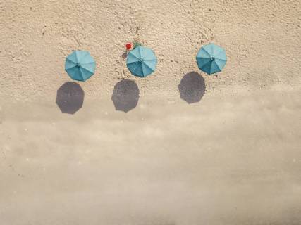 IMAGO Creative, Jahreszeit Sommer, Sonnenschutz Bali, Kuta Beach, three beach umbrellas, aerial view  KNTF02499