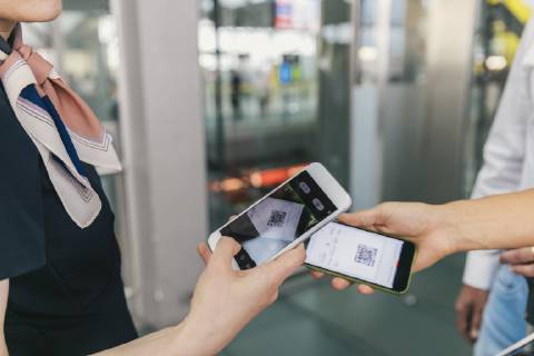 Airline employee scanning QR codes of passengers with smartphone at the airport model released Symbolfoto property released MFF04730