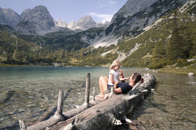 Austria, Tyrol, playful mother and daughter on tree trunk at lake Seebensee model released Symbolfoto  FKF03289