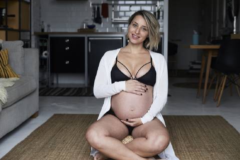Portrait of smiling blonde pregnant woman sitting on the floor at home model released Symbolfoto property released IGGF00726