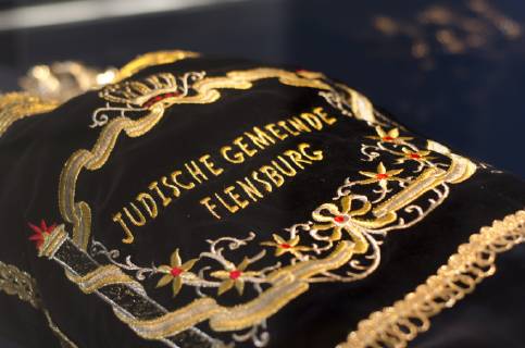 Thora-Rollen der Jüdischen Gemeinde Flensburg im Museumsberg ausgestellt Samtbedeckung auf Thora-Rolle mit Aufschrift Jüdische Gemeinde Flensburg , im Glasschaukasten, am 20.05.2019 in der Schatzkammer des Museumsberges Flensburg,
