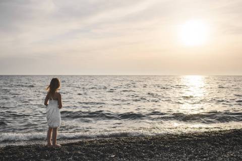 Little girl in white dress looking at sunset over the sea model released Symbolfoto  EYAF00116