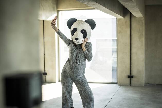 Woman with panda mask standing in office, taking selfie model released Symbolfoto property released  MJRF00180