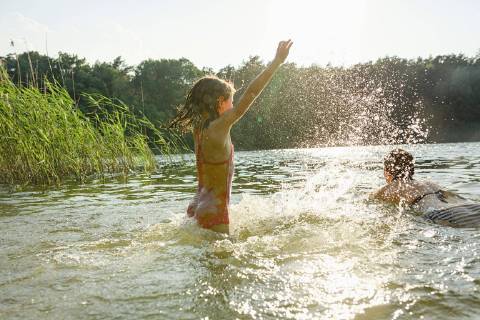 Playful girl splashing and woman swimming in sunny summer lake Germany Brandenburg  Copyright: SvenxHagolani fStopImages1813087
