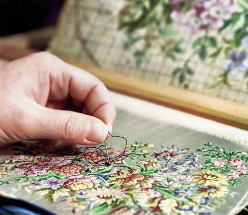 IMAGO Creative: Digitale Welt, Verzicht auf Technologie Sticken als altes Handwerk, Nahaufnahme einer Hand mit Sticknadel auf einer Stickerei mit Blumenmuster Stickarbeit