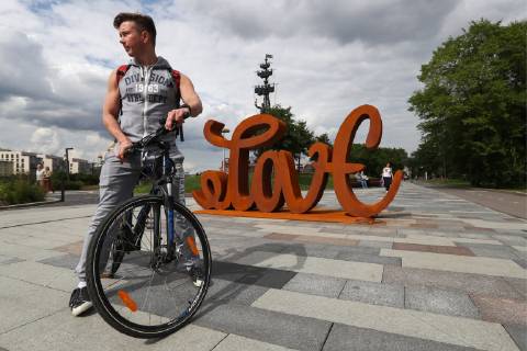 MOSCOW, RUSSIA - JULY 13, 2019: A bicyclist in front of Love Hate, a mobile ambigram sculpture by German contemporary artist Mia Florentine Weiss, unveiled at Muzeon Park as part of her European tour in support of the LoveEurope art action. Stanislav Krasilnikov TASS  TS0B2FEC