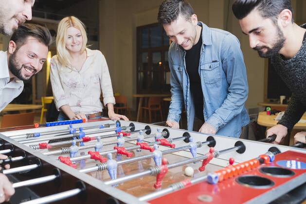 Happy colleagues playing foosball in office model released Symbolfoto property released  FMOF00685