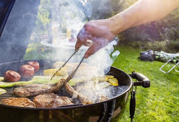 DEU, Deutschland, Münsingen, Baden-Württemberg, 24.08.2019: Grillfest im Garten. Auf dem Rost liegen Steaks vom Rind, Lammkeule, Schweinenacken sowie Tomaten, Mais und Zucchini.