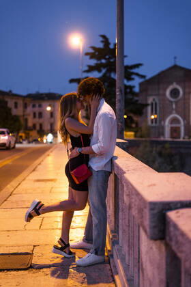 Affectionate young couple kissing inon a bridge at night, Verona, Italy model released Symbolfoto GIOF07023