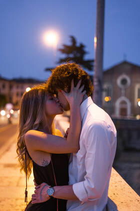 Affectionate young couple kissing inon a bridge at night, Verona, Italy model released Symbolfoto GIOF07025