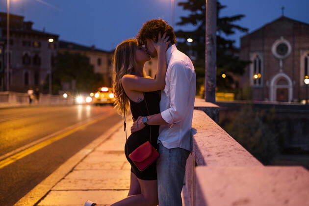 Affectionate young couple kissing inon a bridge at night, Verona, Italy model released Symbolfoto GIOF07026