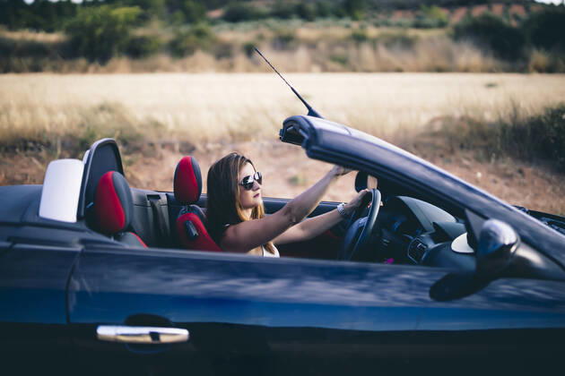 Young woman wearing sunglasses, sitting in her convertible model released Symbolfoto  OCMF00604