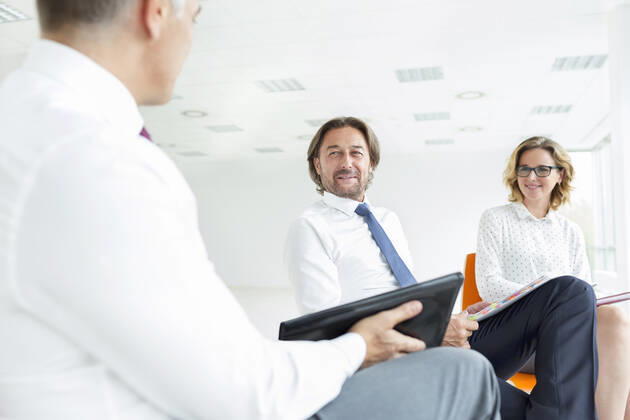 Smiling colleagues looking at businessman while sitting in new office during meeting,model released, Symbolfoto INH_19064_12277