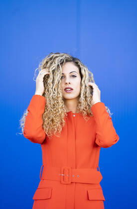 Creative Highlights Symbolfotos Portrait of young woman wearing red dress in front of blue background model released Symbolfoto  DAMF00148