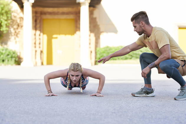 Fitness coach practicing with young woman outdoors in the city model released Symbolfoto  JNDF00091