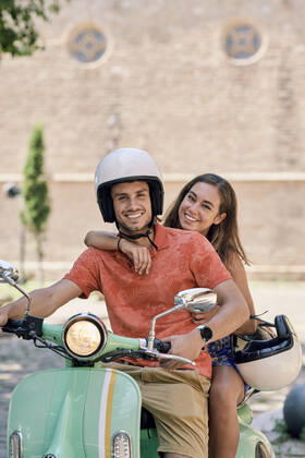 IMAGO Creative, Jahreszeit Sommer, Sommer in der Stadt Portrait of a smiling young couple on a vintage motor scooter model released Symbolfoto  JNDF00124