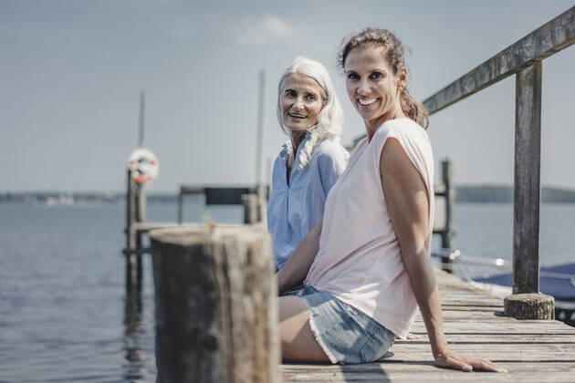 Mother and daughter sitting on jetty, relaxing at the sea model released Symbolfoto  JOSF03708