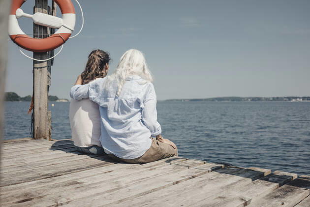 Mother and daughter looking at the sea, sitting on jetty, rear view model released Symbolfoto  JOSF03710