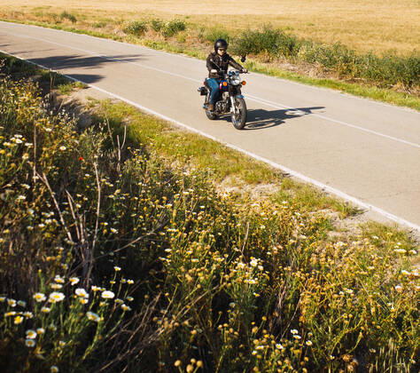 young man riding his black motorcycle on the road with his helmet on Spain, Andalusia, Seville CR_FAGU191022-207988-01