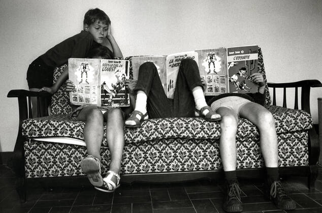 Lecture Enfants lisant des bandes-dessinees de Lucky Luke. Photographie de 1969 par Jean Pottier. Vie quotidienne annees 60. Credit : Jean Pottier KHARBINE-TAPABOR.