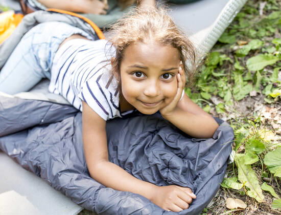 Little girl lying on sleeping bag, looking at camera model released Symbolfoto  WESTF24487