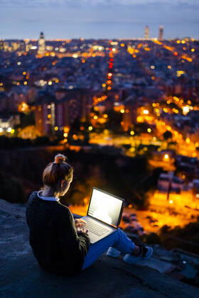 Young woman sitting on railing above the city using cell phone, Barcelona, Spain model released Symbolfoto GIOF07944