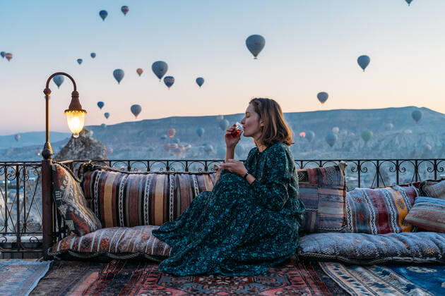 Woman drinking early morning tea with hot air balloons in Cappadocia GoÂ¶reme, NevAÂüehir, Turkey ,model released, Symbolfoto CR_SEAK200116B-287292-01