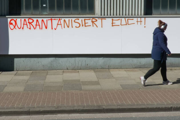 Bilder des Jahres 2020, News 03 März News Bilder des Tages Zur Eindämmung des Coronavirus wurden Geschäftsschließungen angeordnet und werden Ausgangssperren diskutiert, das Foto zeigt eine Fußgängerin vor einem Graffiti, Schriftzug an einem gebäude mit der Aufschrift: Quarantänisiert Euch, 22.03.2020, Bremen (Deutschland), News, Feature, Coronavirus Bremen