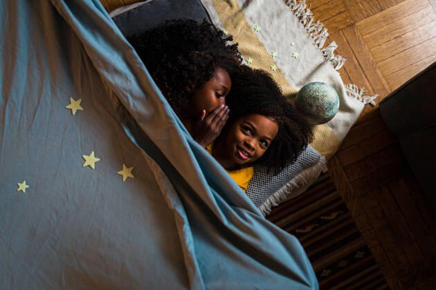 IMAGO Creative: Jahreszeit Winter, Fantasievoll drinnen spielen Overhead view of girl whispering with sister while relaxing at home New York, NY, United States ,model released, Symbolfoto ,property released CR_LIWEEE200227-318420-01