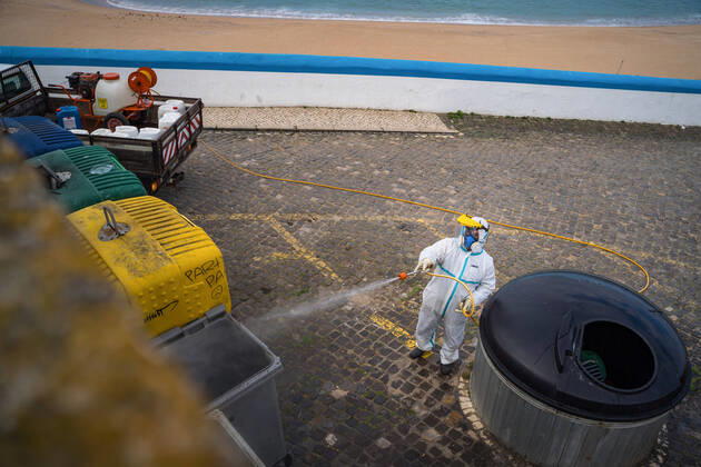 April 14, 2020, Ericeira, Portugal: An employee of the Ericeira parish council, equipped with the recommended protective materials, disinfects the recycling tanks with a solution based on hypochlorite (bleach)..The municipality of Mafra had 70 cases of COVID-19 pandemic. In order to prevent the spread of the virus, the Ericeira Parish Council perform weekly street disinfection. Ericeira Portugal - ZUMAs197 20200414_zaa_s197_182 Copyright: xHenriquexCasinhasx