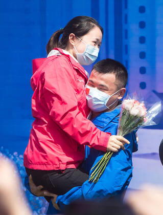 (200415) -- WUHAN, April 15, 2020 -- Hu Zhimin (R), a nurse with Zhongnan Hospital of Wuhan University, holds his colleague Zeng Yingying after professing his love for her during the closing ceremony at Leishenshan (Thunder God Mountain) Hospital in Wuhan, capital of central China s Hubei Province, April 15, 2020. Wuhan Leishenshan (Thunder God Mountain) Hospital ceased operation in Wuhan on Wednesday as the coronavirus epidemic wanes. ) CHINA-HUBEI-WUHAN-LEISHENSHAN HOSPITAL-RETIRING (CN) XiaoxYijiu 
