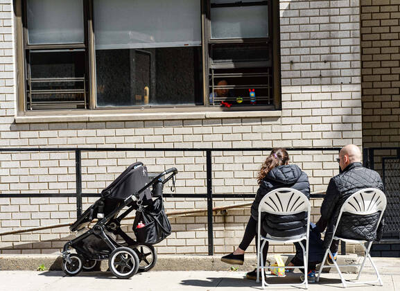 April 15, 2020, New York Manhattan, USA: Family members sitting in a chair on the sidewalk to visit family members sick with the coronavirus. Death toll in N.Y.10,367 as confirmed cases 106,813 04 15 20. New York Manhattan Randalls Island Icahn Stadium. New York Manhattan Upper East Side. New York Manhattan USA - ZUMAs252 20200415_znp_s252_004 Copyright: xMarcusxSantosx